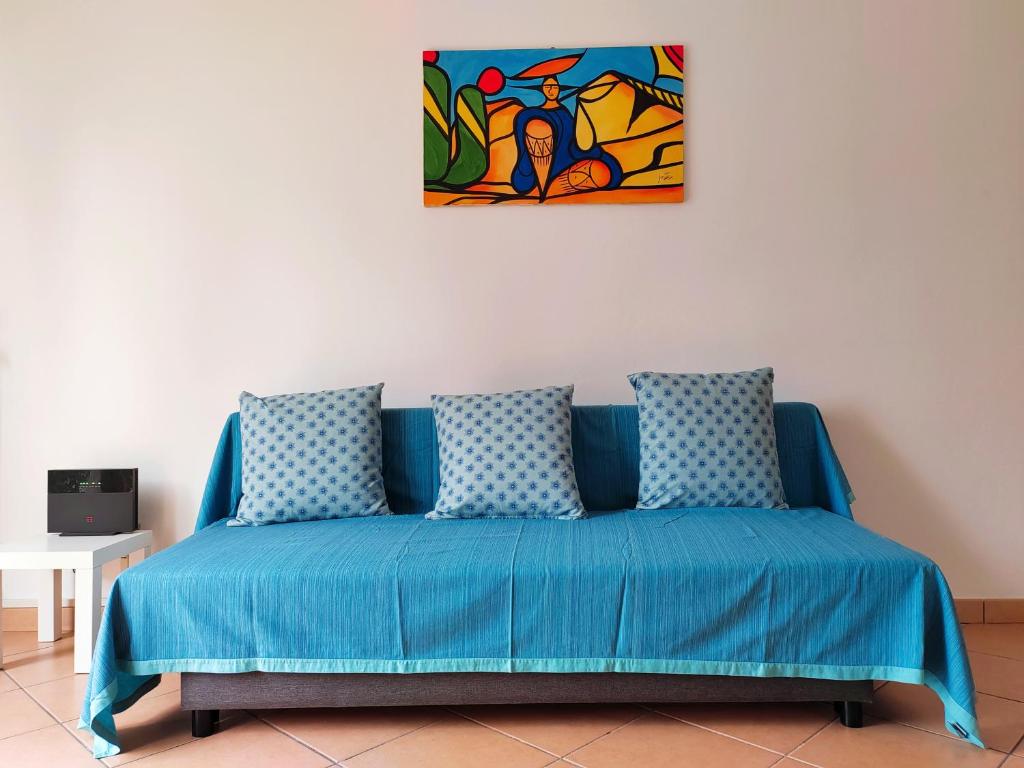 un sofá azul en una habitación con una pintura en la pared en IEO -Humanitas - SUNNY HOUSE - Comodissimo, en Locate di Triulzi