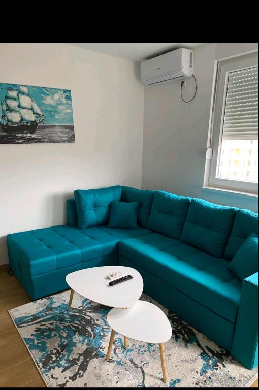 a living room with a blue couch and a table at Cozy Apartment in Lukavica