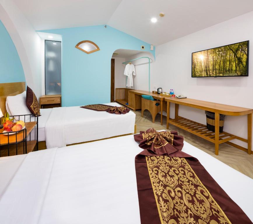a hotel room with two beds and a desk at Prime New Hotel in Nha Trang