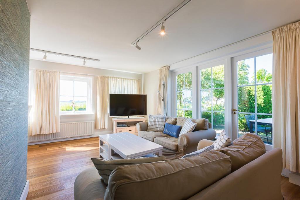 ein Wohnzimmer mit einem Sofa und einem TV in der Unterkunft Hello Zeeland - Vakantiehuis Brouwerijweg 43-3 in Domburg