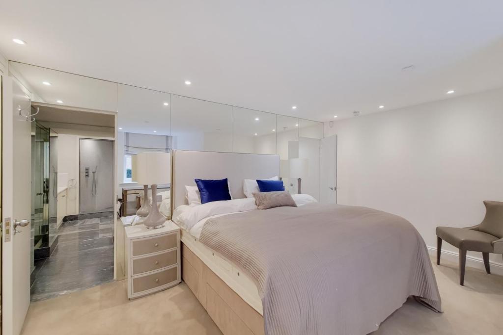 a white bedroom with a large bed and a chair at Sir Hans Sloane Apartments in London