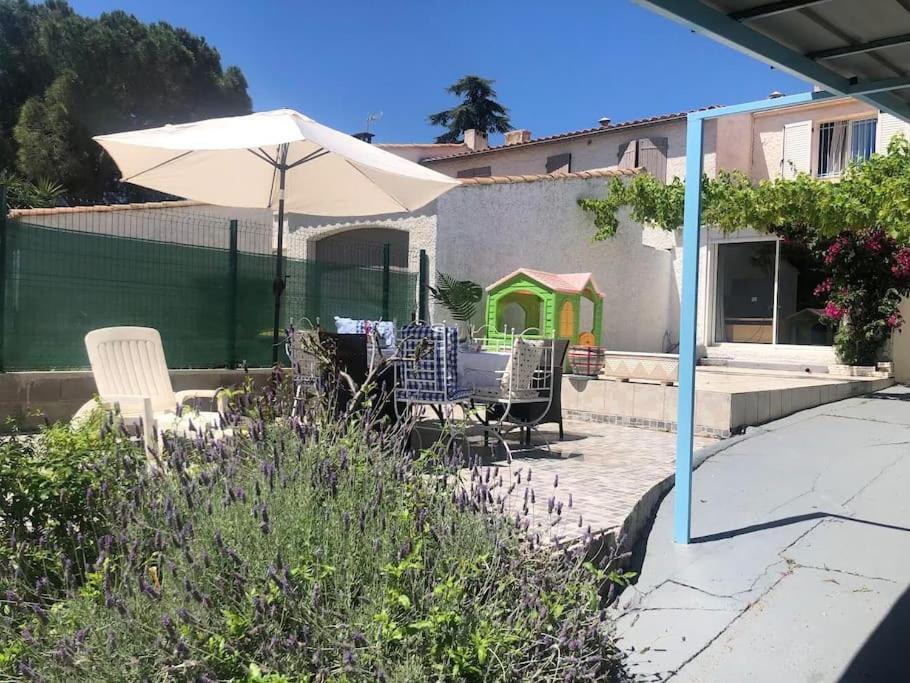 un patio con mesa y sombrilla en Les Micocouliers - Spacieuse maison,4chambres ,avec Jardin- Parking -Wifi en Béziers