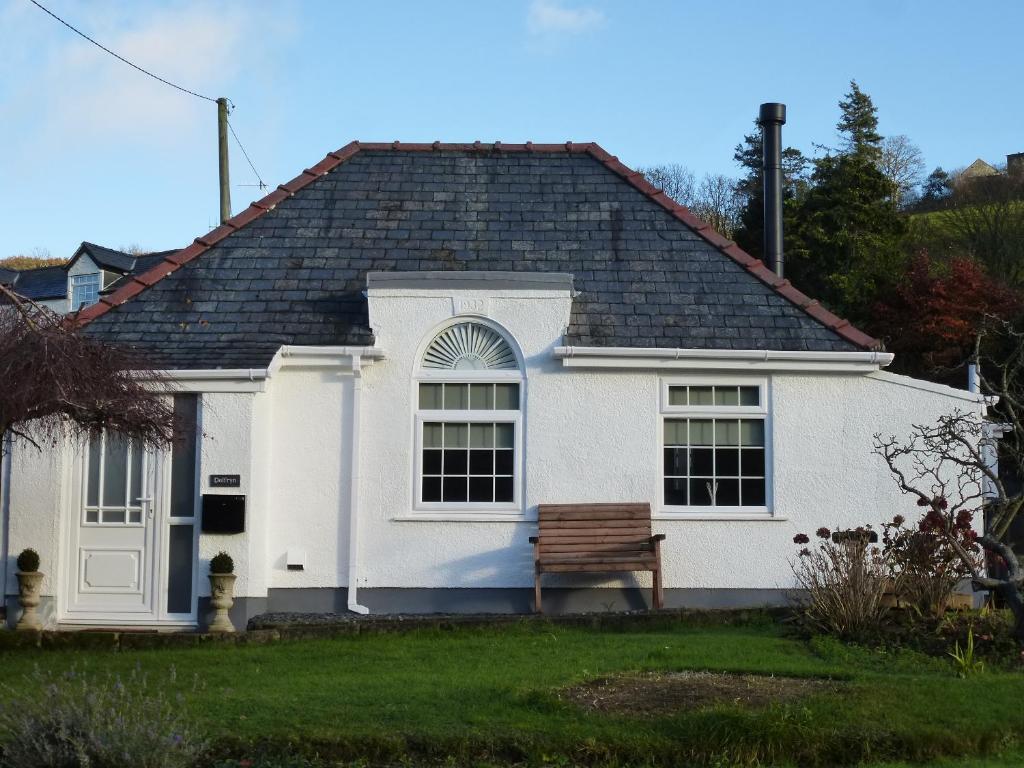 a white house with a bench in the yard at Delfryn Holiday Cottage in Colwyn Bay