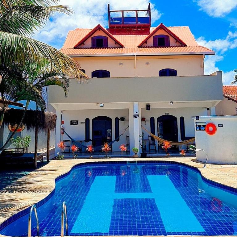 a house with a swimming pool in front of a house at Hostel Praia Centro Itanhaém in Itanhaém