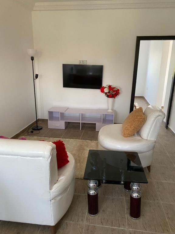 een woonkamer met twee witte banken en een tv bij Our Nice Home in Kaduna