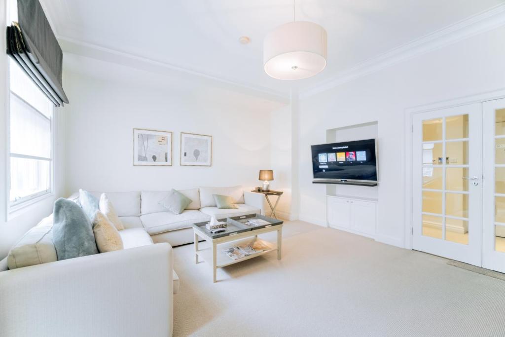 sala de estar blanca con sofá blanco y TV en Clarges - Grand Park Street Apartments, en Londres