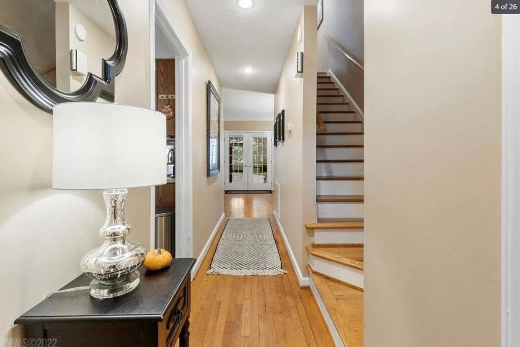 a hallway with a table with a lamp and a staircase at The Red Door 2-bedroom townhouse near VT & RU in Radford