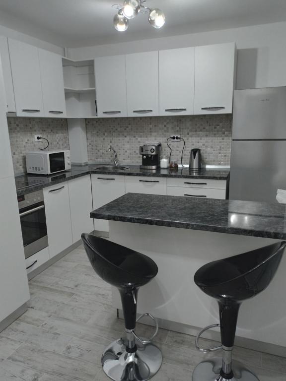a kitchen with white cabinets and black counter stools at Apartament Central in Oradea
