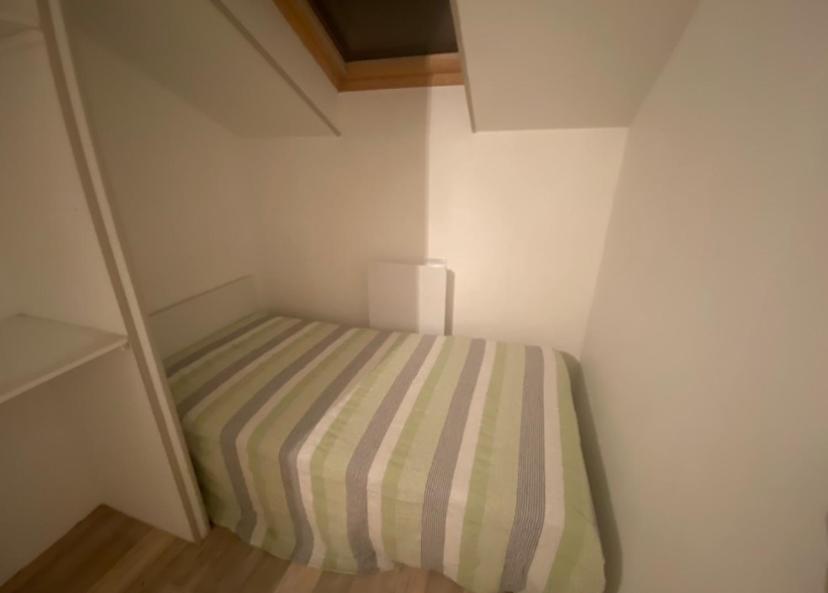 a small bedroom with a striped bed in a room at Gîte du Messager 6/8 personnes in La Machine