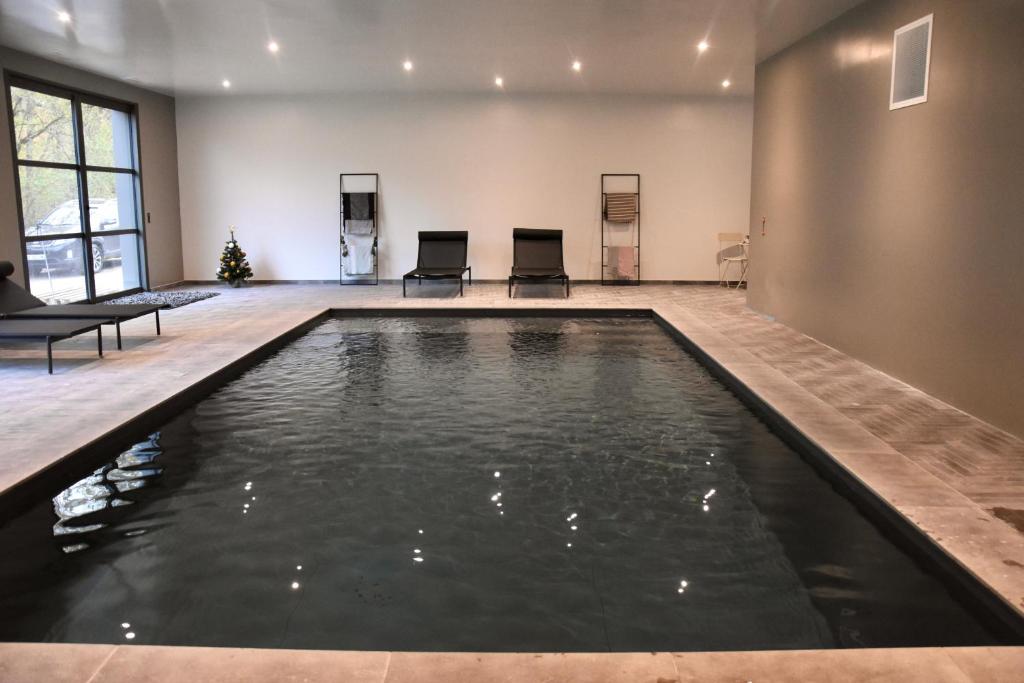 una piscina en una habitación grande con 2 sillas en Domaine de La Soudelle en Chanceaux-sur-Choisille