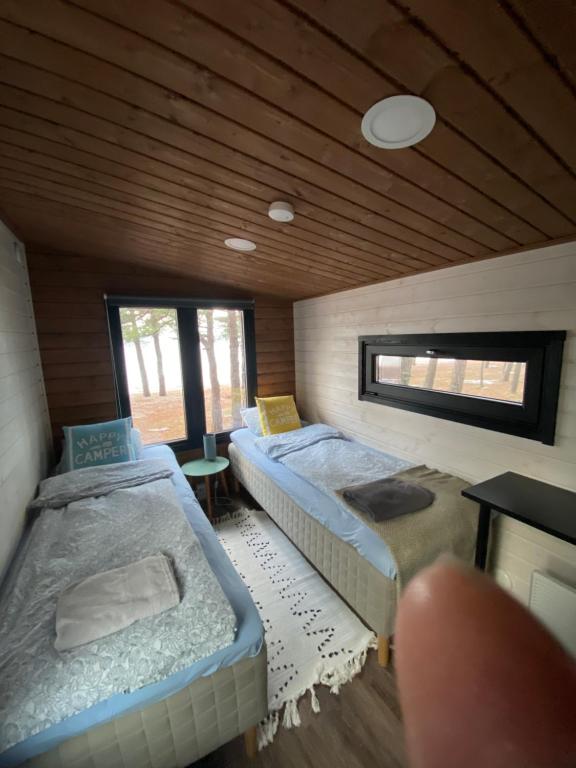una camera con 2 letti in una stanza con soffitto in legno di Beach Cottage a Hanko