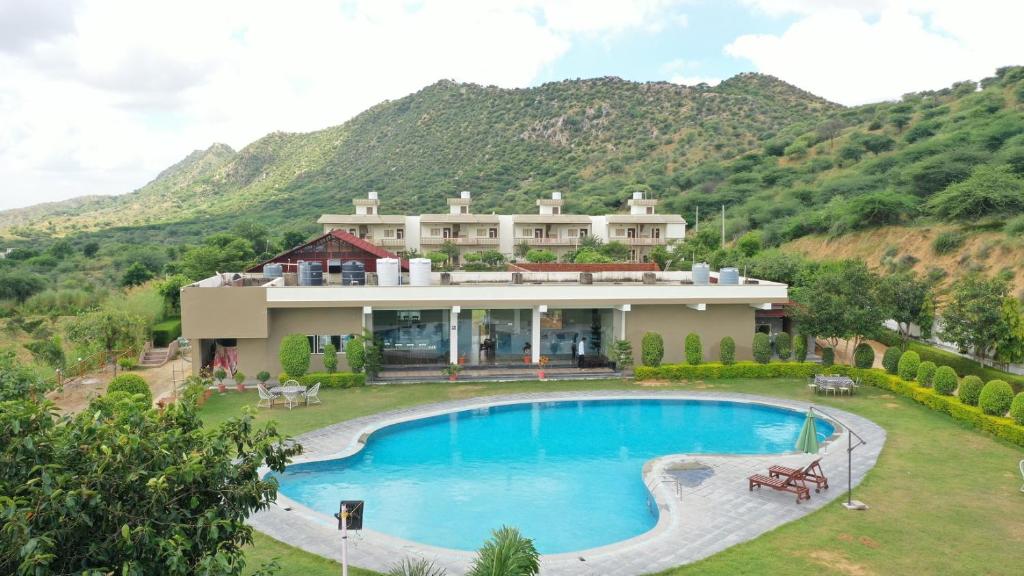 una casa con piscina frente a una montaña en Amar Bagh Resort, en Pushkar
