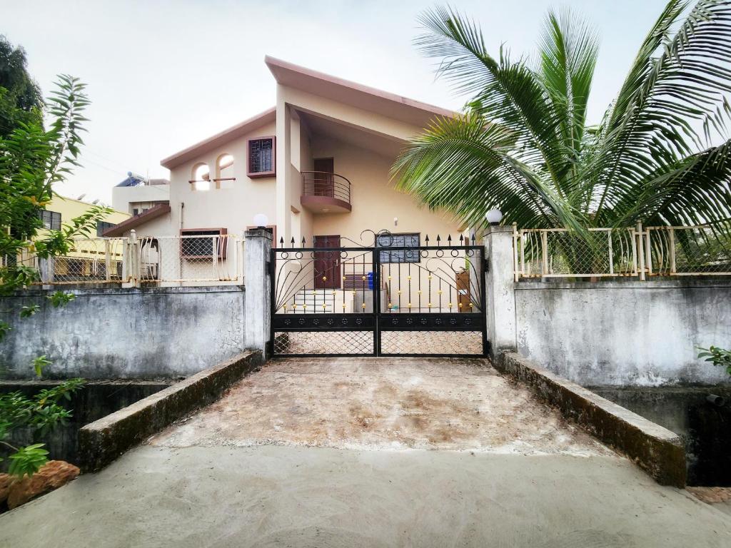 une maison avec un portail et un palmier dans l'établissement VedGanga Plus Villa - Homestay, à Kolhapur