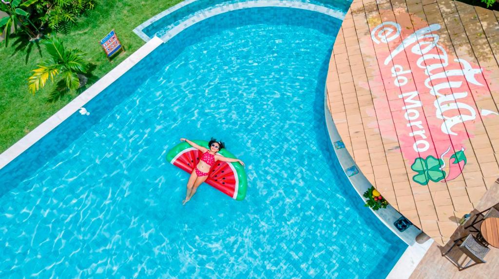 une femme en gilet de sauvetage flottant sur une planche de surf dans une piscine dans l'établissement Pousada Patuá do Morro, à Morro de São Paulo