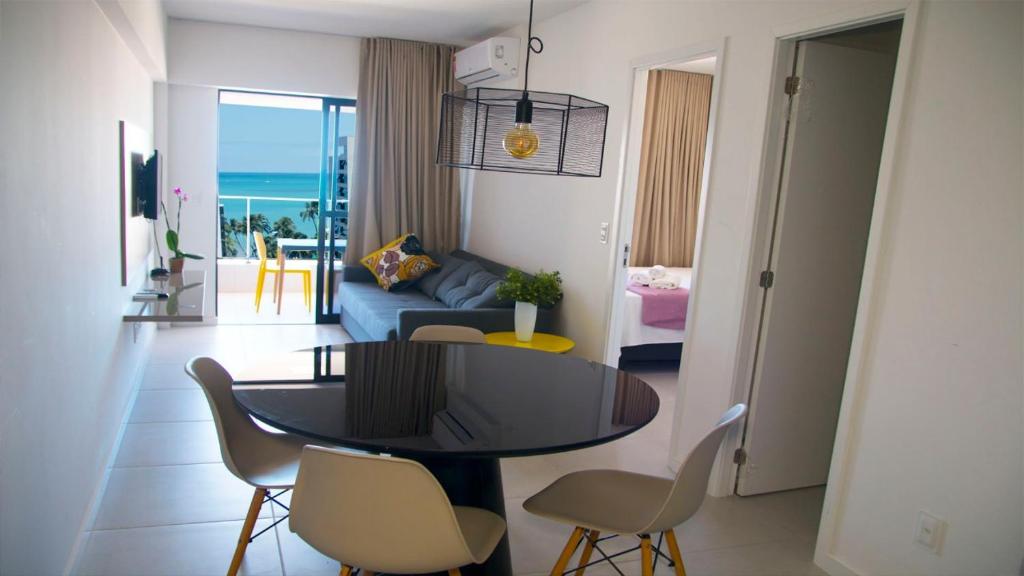 a living room with a table and chairs and a couch at APARTAMENTO ALTO LUXO A 4MIn DO MAR TIME in Maceió