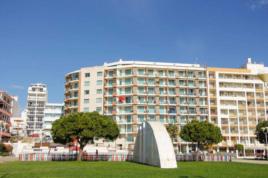 un grande edificio con una scultura in un parco di Monte da Praia a Monte Gordo