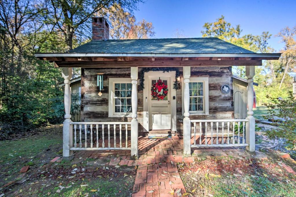 ein winziges Haus mit einem Weihnachtskranz an der Tür in der Unterkunft Historic Marshall Log Cabin Less Than 1 Mi to Dtwn! in Marshall