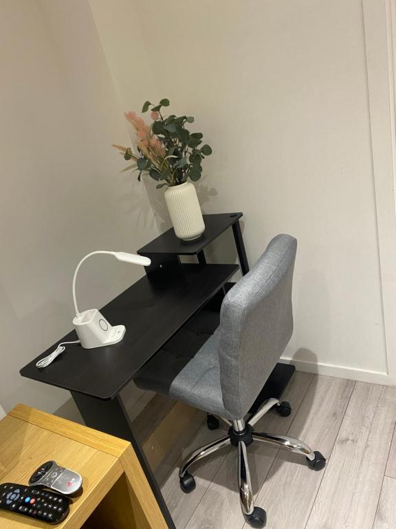 a black desk with a chair and a vase of flowers at SPECIAL PROMO! Perfect Group Accommodation, 3 Bathrooms Perfect for Contractors and Businesses with relocation Requirement near Harwich Sea Port in Harwich