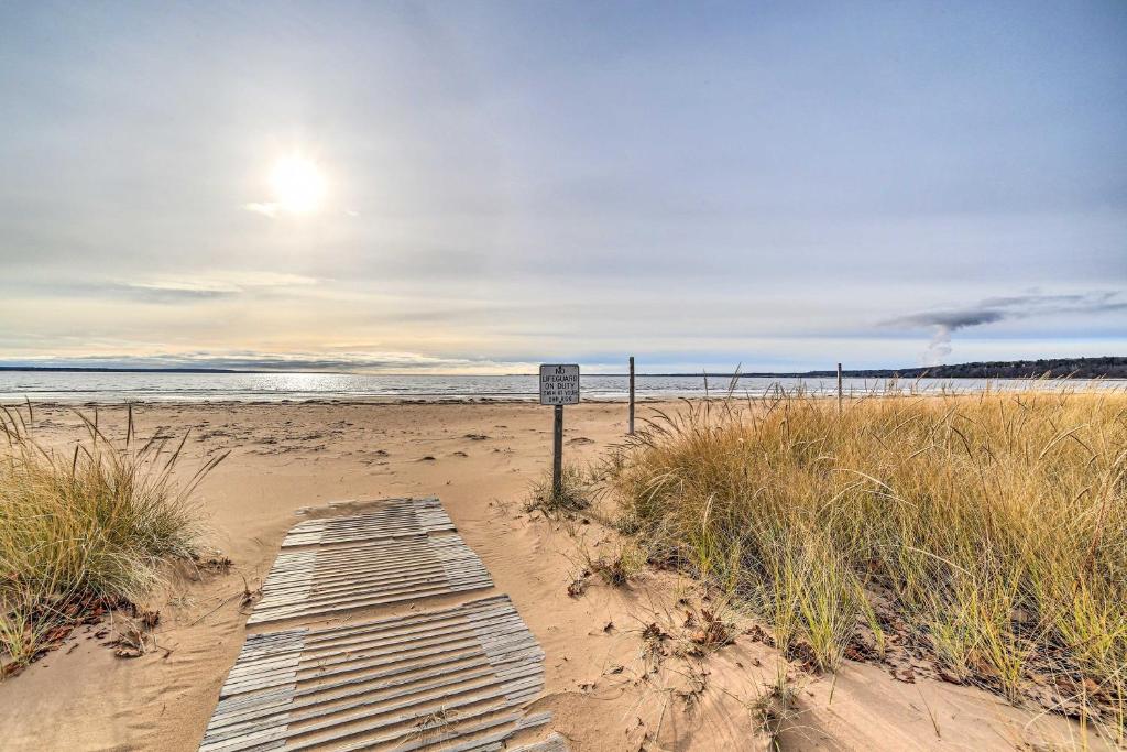 een houten loopbrug op een zandstrand met de oceaan bij Spacious Michigan Home with Private Hot Tub in Gladstone