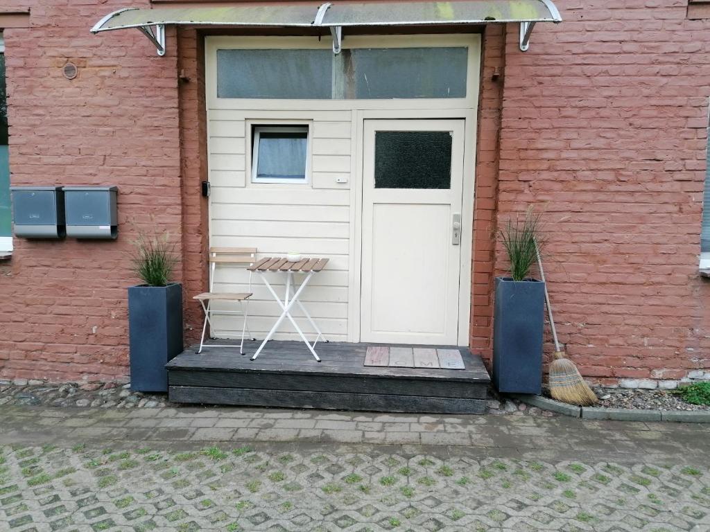 een witte deur op een bakstenen gebouw met een stoel bij Schöne Wohnung, Zwei Schlafzimmer, Zentrumsnah, Erdgeschoss in Greifswald in Greifswald