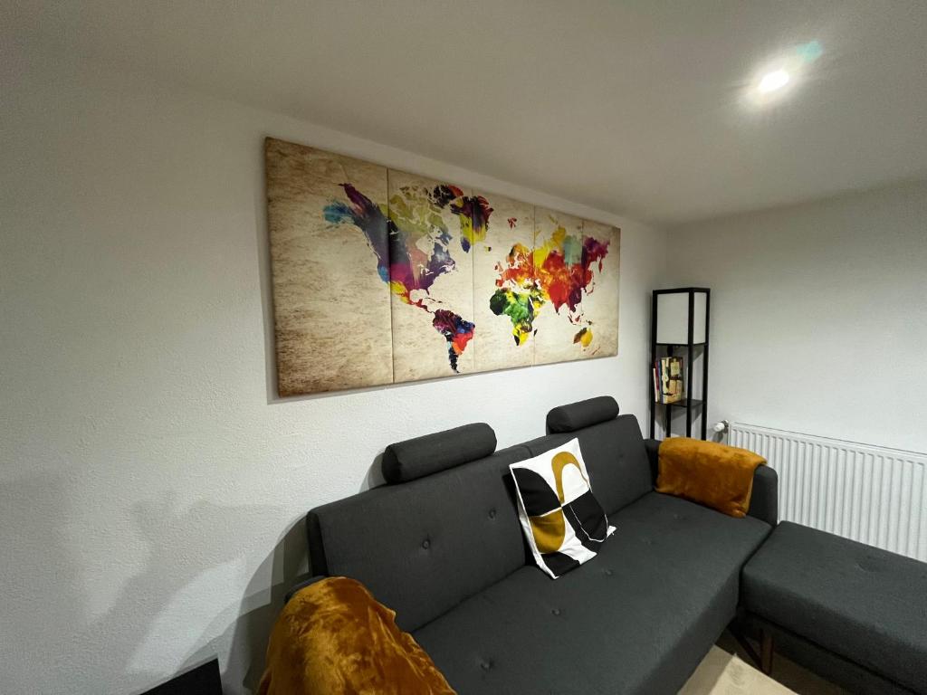 een woonkamer met een bank en een kaart aan de muur bij Chouett'Appart proche frontières in Village-Neuf