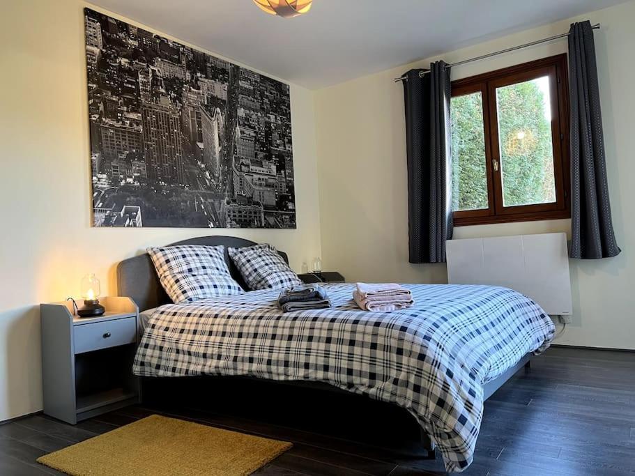 una camera da letto con un letto con una coperta scozzese e una finestra di Appartement calme au coeur du jardin a Violaines