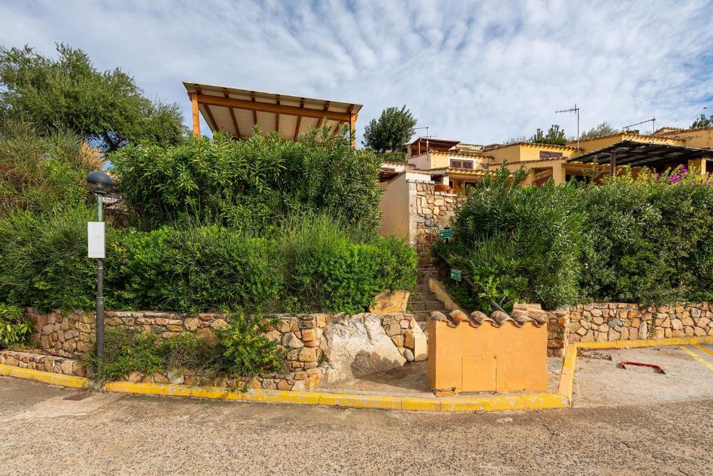 a house with a stone wall and bushes at VILLA CLAUDIO e LUNETTA in Villasimius