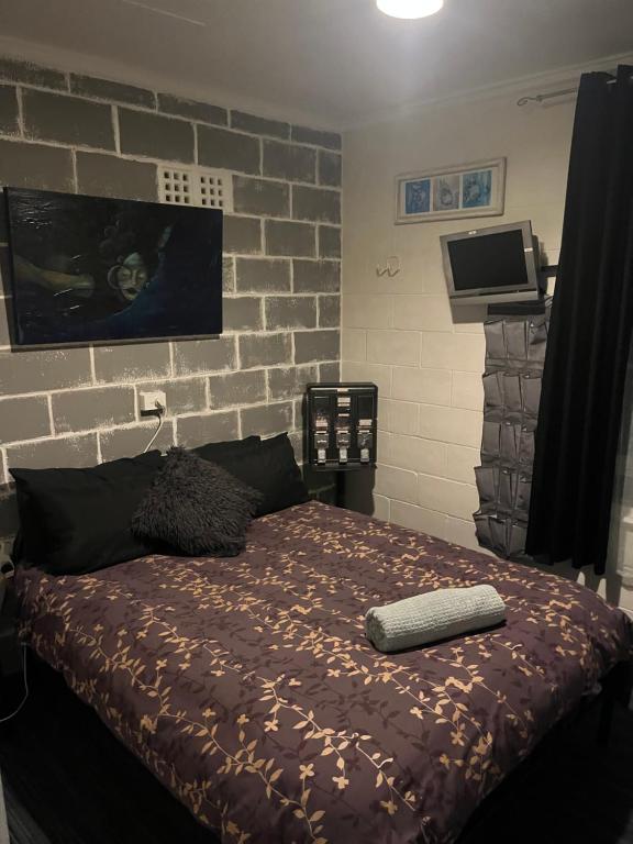ein Schlafzimmer mit einem Bett mit Ziegelwand in der Unterkunft The downstairs delight 2brm , 6+ guests & dogs ok in Lake Munmorah