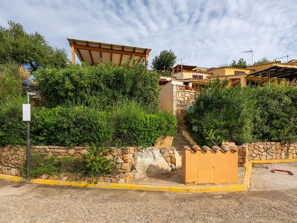 a house with a stone wall and bushes at VILLA CLAUDIO e LUNETTA in Villasimius