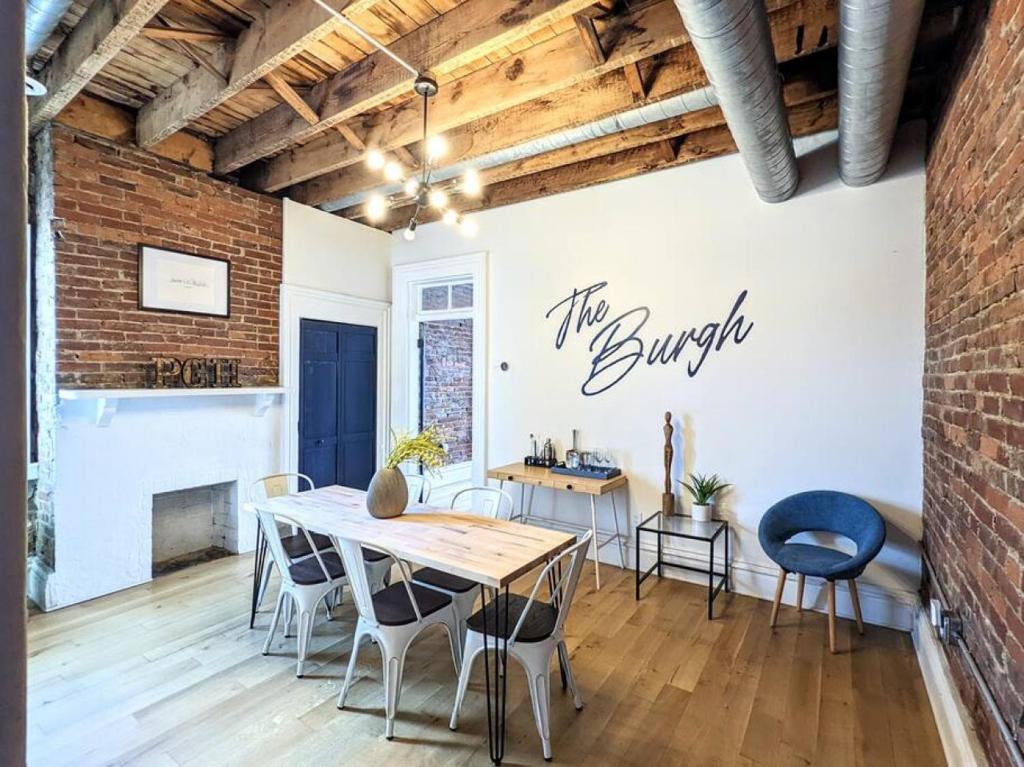 uma sala de jantar com uma parede de tijolos e uma mesa e cadeiras em HostWise Stays - Industrial Vintage Style, Minutes to Downtown em Pittsburgh