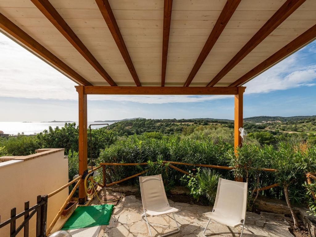 a patio with white chairs and a wooden pergola at VILLA CLAUDIO e LUNETTA in Villasimius