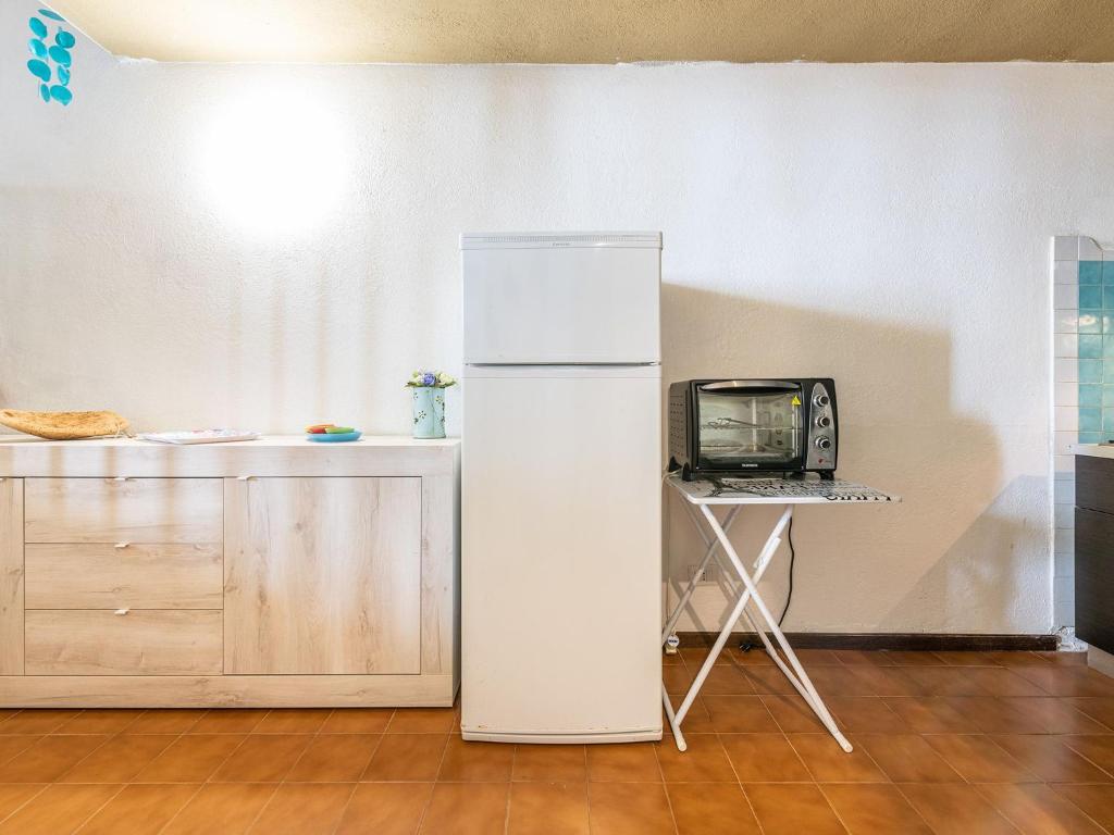 a white refrigerator in a kitchen with a tv at VILLA CLAUDIO e LUNETTA in Villasimius