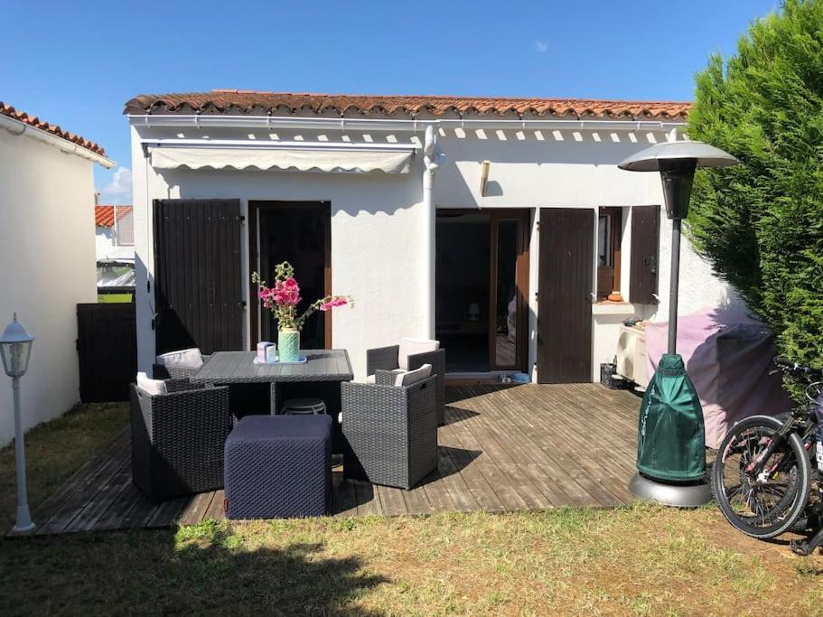 patio ze stołem i krzesłami na podwórku w obiekcie Agréable maison, plage à 400m, jardin, piscine et tennis w mieście Saint-Palais-sur-Mer