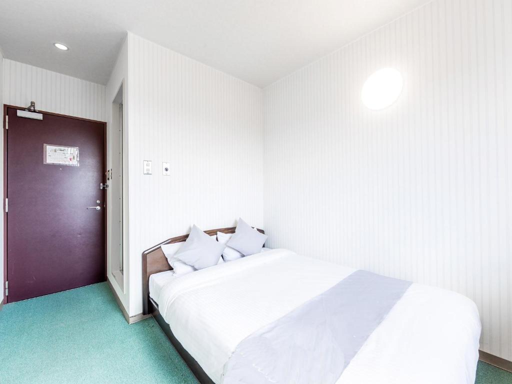 um quarto com uma cama branca e uma porta roxa em HOTEL SHAROUM INN - Vacation STAY 04976v em Hakodate