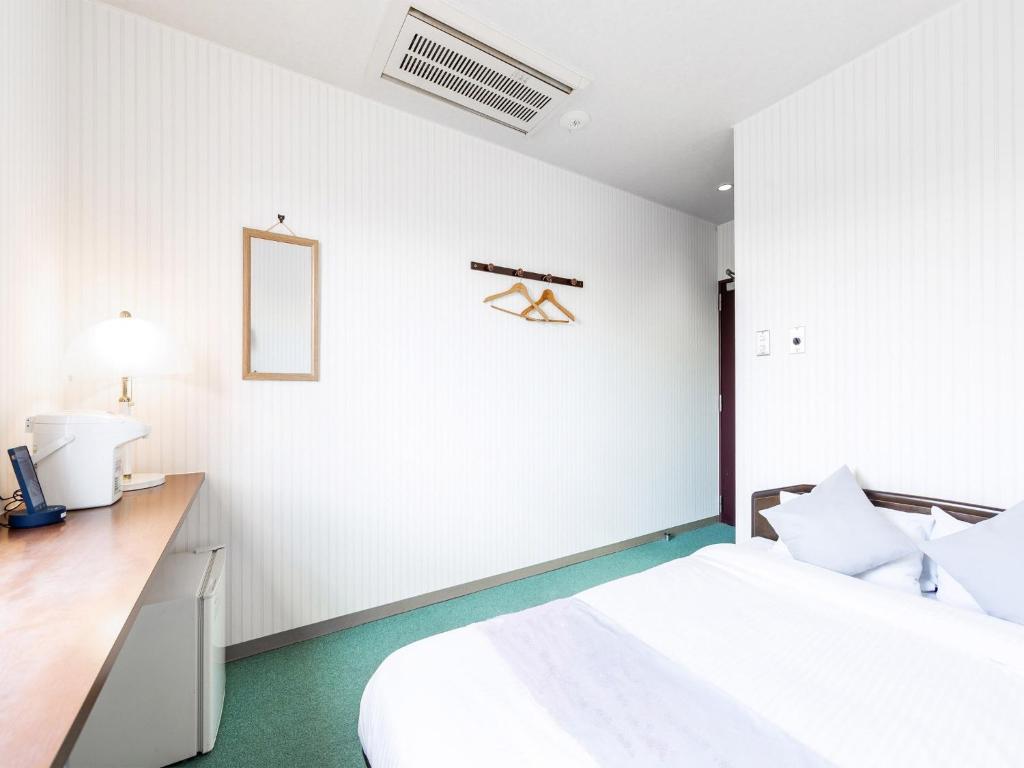 a bedroom with a bed and a desk with a mirror at HOTEL SHAROUM INN - Vacation STAY 04975v in Hakodate