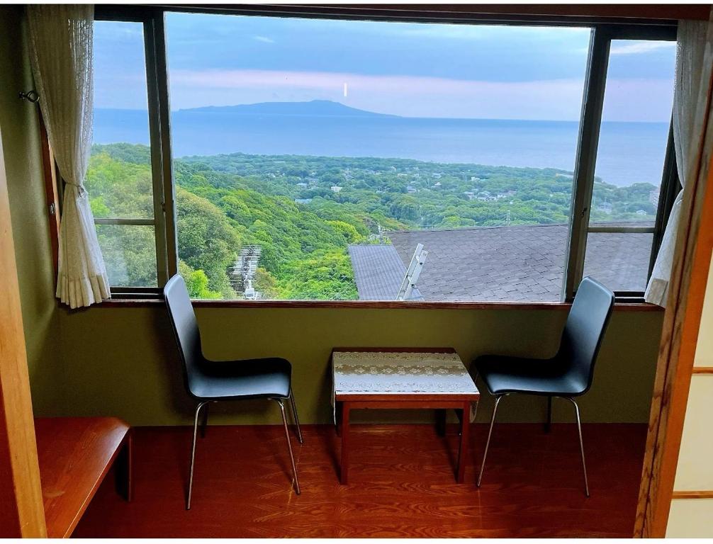 einen Tisch und zwei Stühle in einem Zimmer mit einem großen Fenster in der Unterkunft Izu One Club - Vacation STAY 10342v in Futo