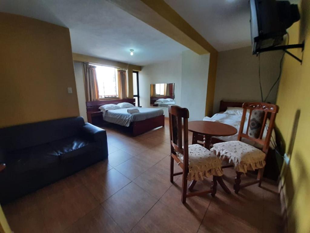 sala de estar con mesa, sillas y sofá en Hostal Don Cristobal, en Ayacucho