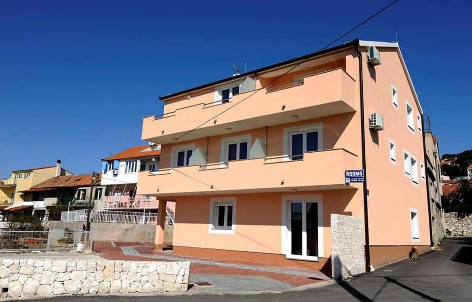 a large pink building with a blue sky behind it at Apartments & Rooms Krecak Sibenik in Šibenik