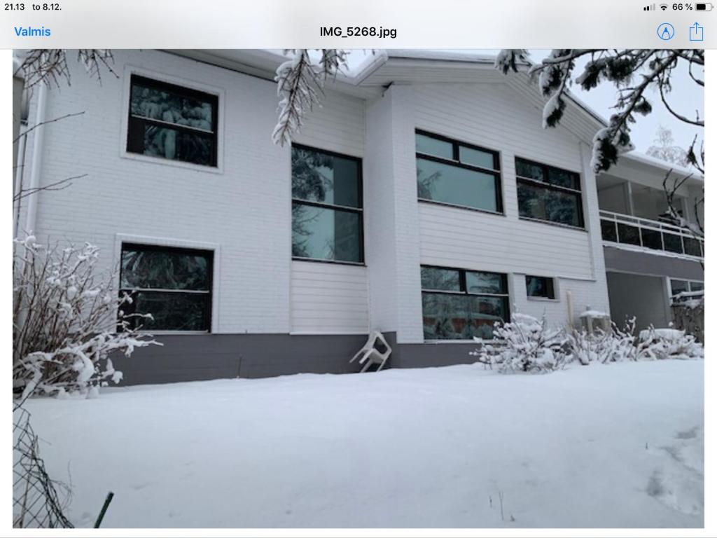 a white house with snow in front of it at Revontuli Apartments in Rovaniemi