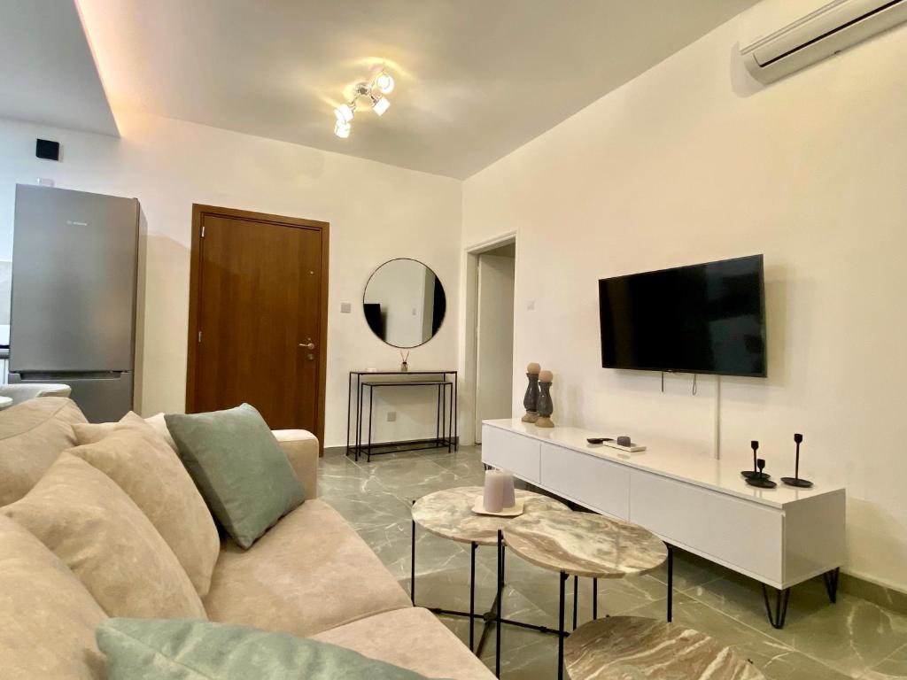 ein Wohnzimmer mit einem Sofa und einem Flachbild-TV in der Unterkunft White Arches Apt #2 by TrulyCyprus in Limassol