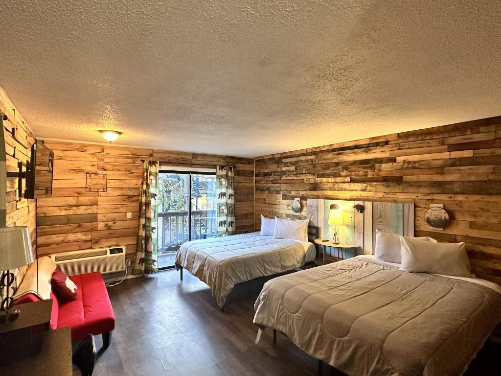 a bedroom with two beds and a wooden wall at Ski Mountain Lodge in Gatlinburg