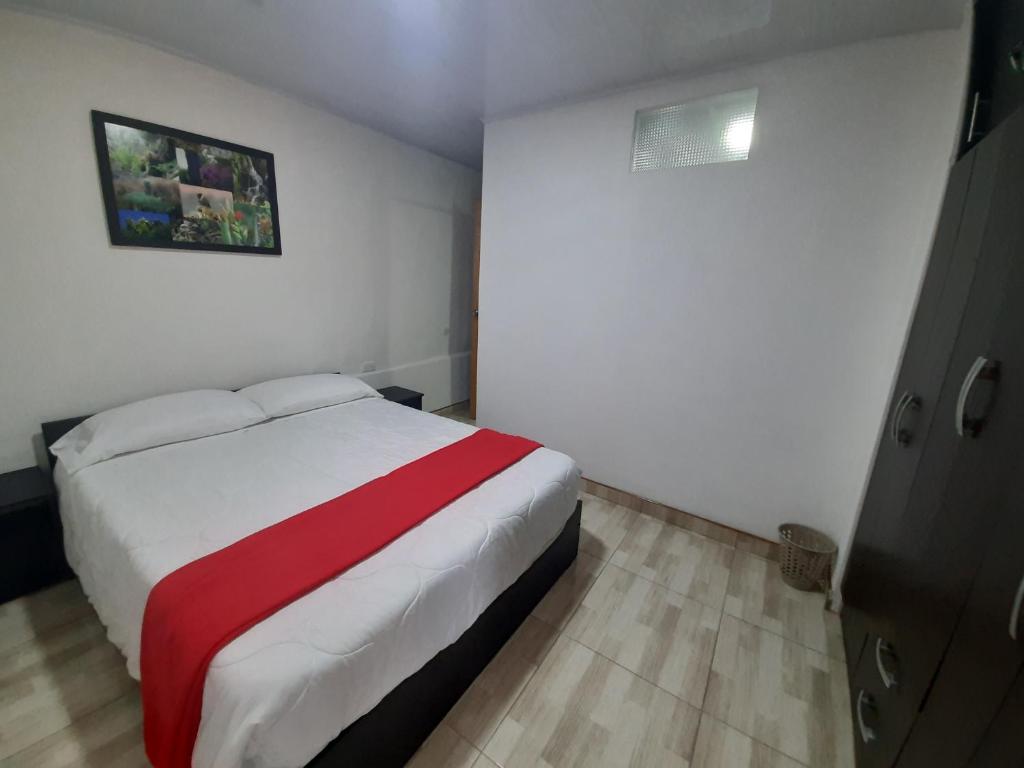 Schlafzimmer mit einem Bett mit einer roten und weißen Decke in der Unterkunft Acogedora casa cerca al centro in Manizales