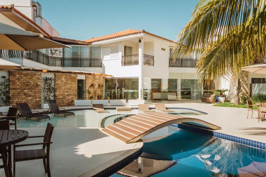 an outdoor patio with a swimming pool and a house at Hotel Boutique Recanto da Passagem in Cabo Frio