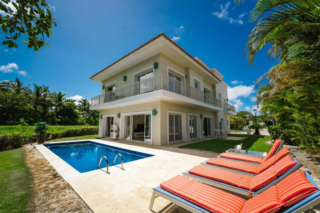a house with a swimming pool and lounge chairs at Private Iberosta Villa Lagoon 4BDR, Beach, Pool - FREE GolfCart in May in Punta Cana