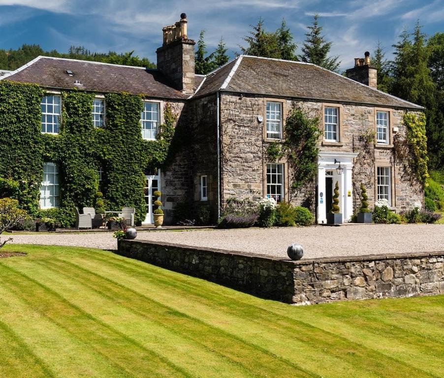 an old stone house with a green lawn at The Old Manse of Blair, Boutique Hotel & Restaurant in Blair Atholl