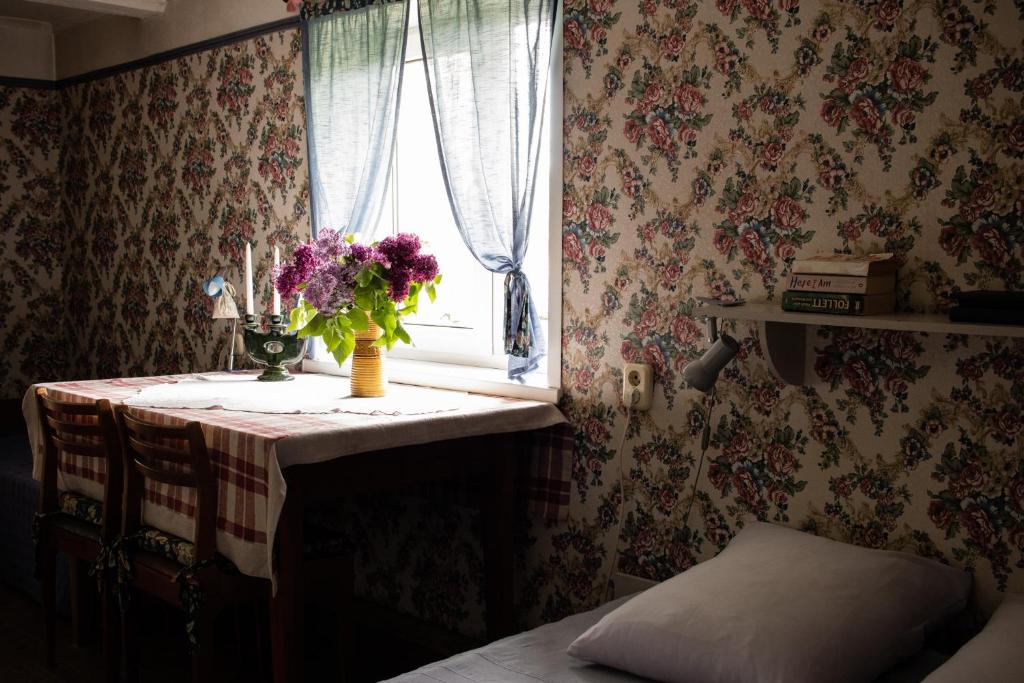 a table with a vase of flowers and a window at Coastal Home Muini Ūši in Kolka