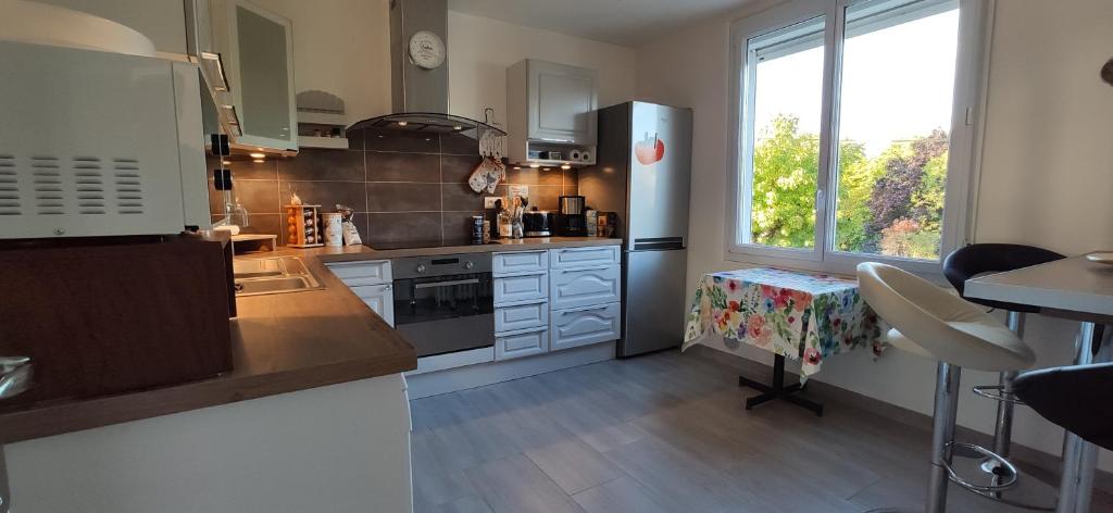 a kitchen with white cabinets and a large window at Magnifique maison familiale située à MORLAIX in Morlaix