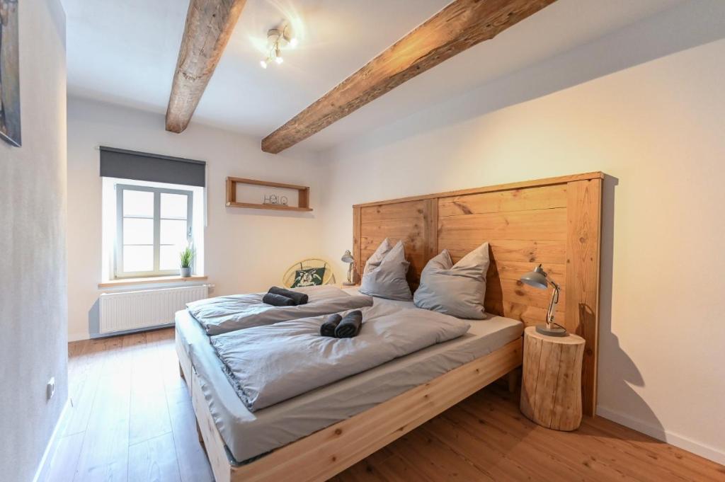 a bedroom with a large bed with a wooden headboard at FarmHouse Eckartsberg im Zittauer Gebirge - Gemütliche und moderne Ferienwohnungen mit Terrasse in Eckartsberg