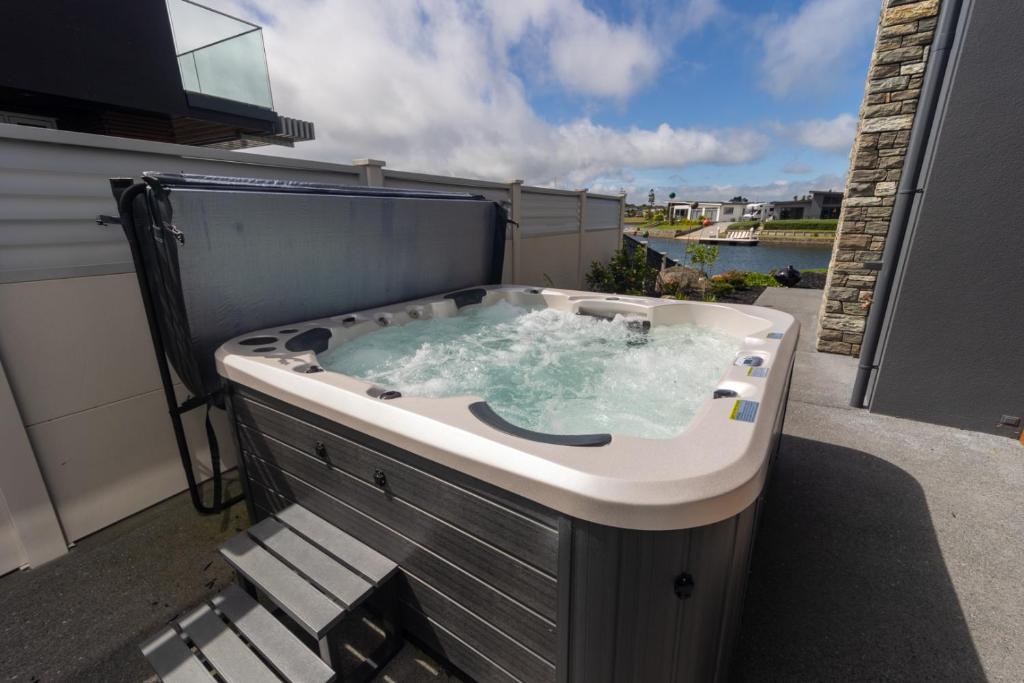 a jacuzzi tub on the balcony of a house at Marsden Cove Canal Haven with Spa Pool in One Tree Point