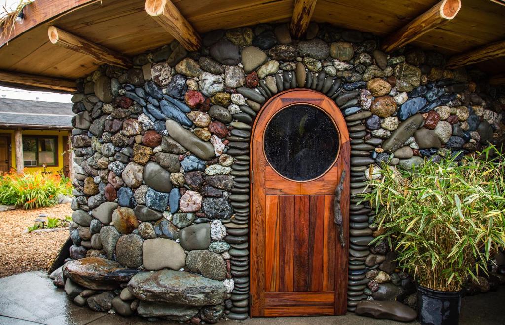 a stone house with a wooden door and a rock wall at The Front Porch Hidden Oasis in Arcata